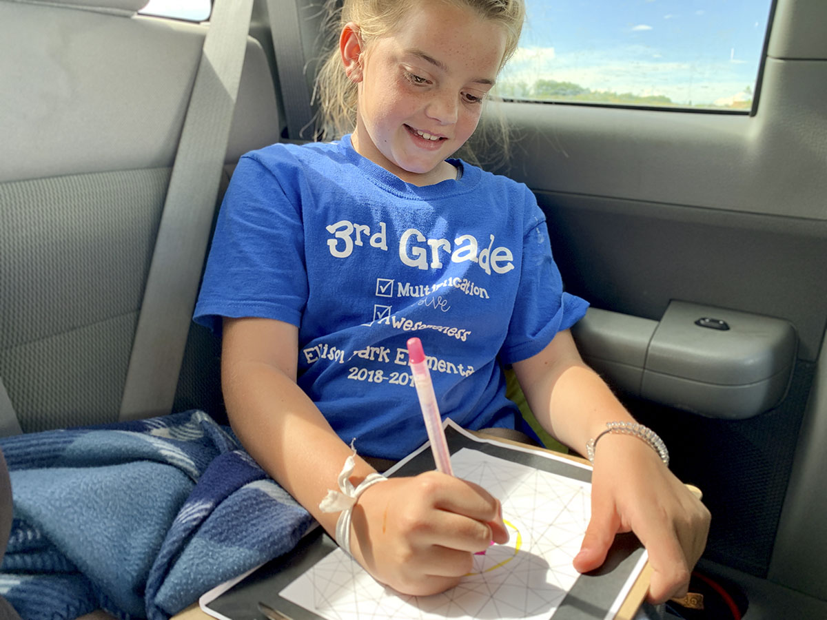 Girl in car coloring while on a road trip